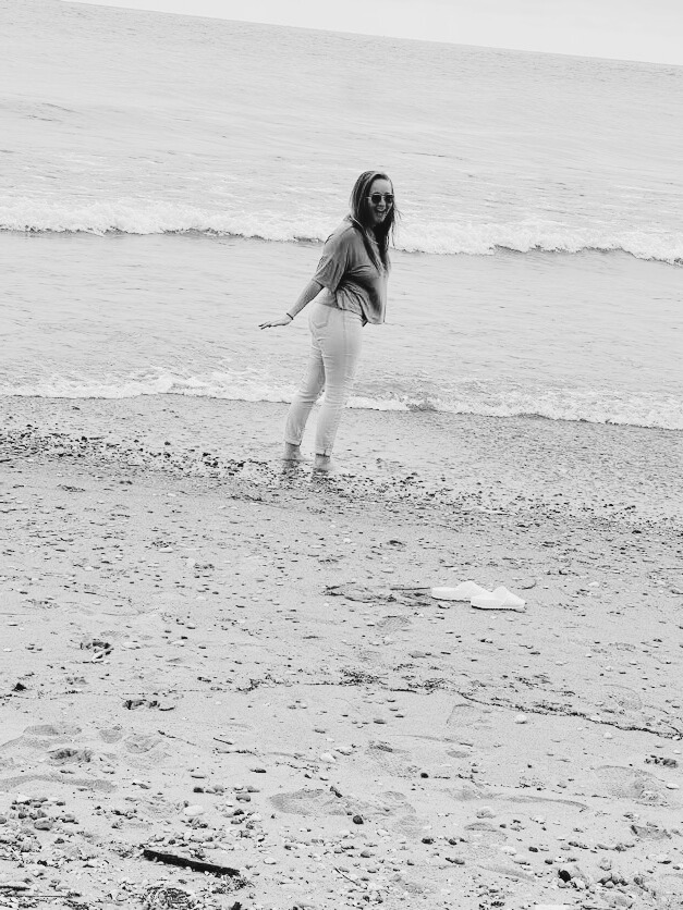 Kristen B. Lenzen looking back over her shoulder at the beach, smiling